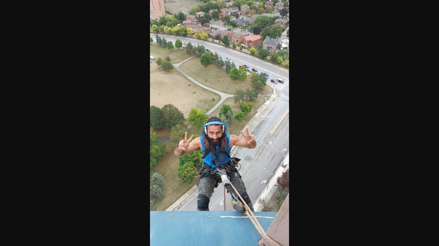 ClearGlass.ca rope access technician suspended from building